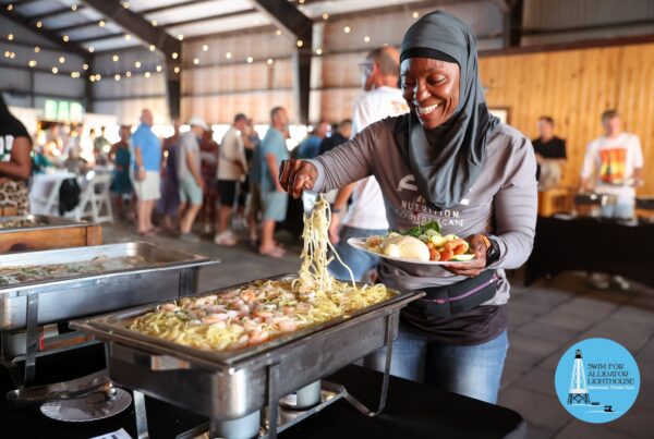 Smiling person filling a plate from a buffet