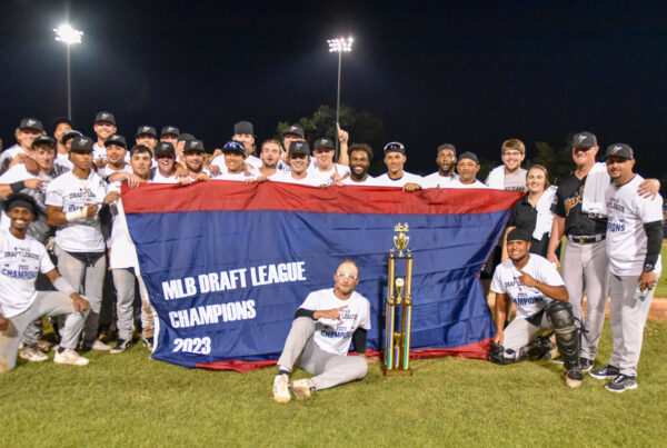 WVBB players pose on the field with the MLB Draft League Champions banner