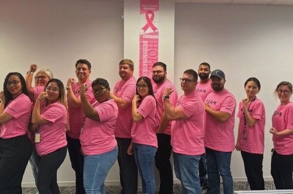 ROAR associates pose in pink shirts for breast cancer awareness