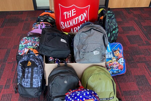 Backpacks surround The Salvation Army donation bin
