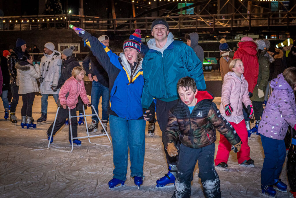 Ice at Canalside on a busy night, with two people holding hands smiling at the camera