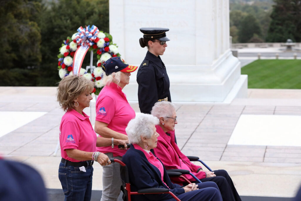 Two veterans and their support people stand with a military member
